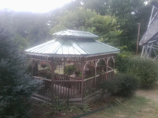 Green metal roof on a backyard gazebo surrounded by garden beds in Newport